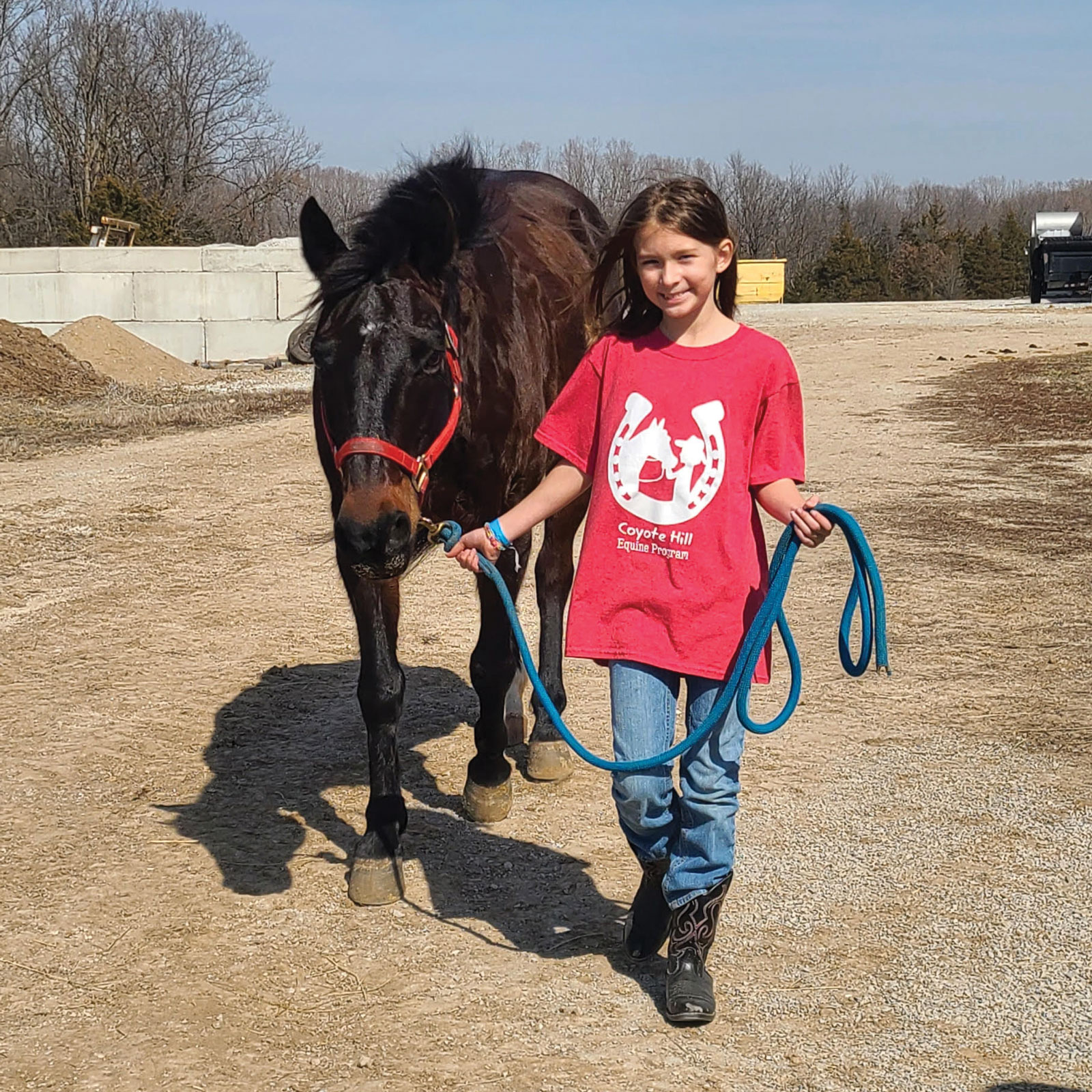 A Coyote Hill rider leading a horse.