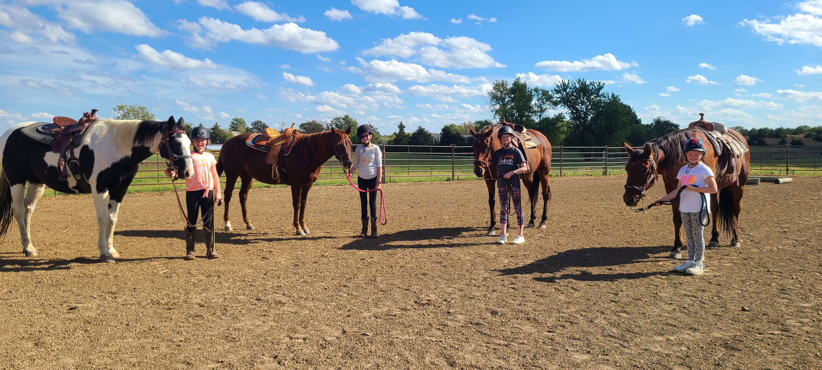 Four Coyote Hills riders standing with their horses. 