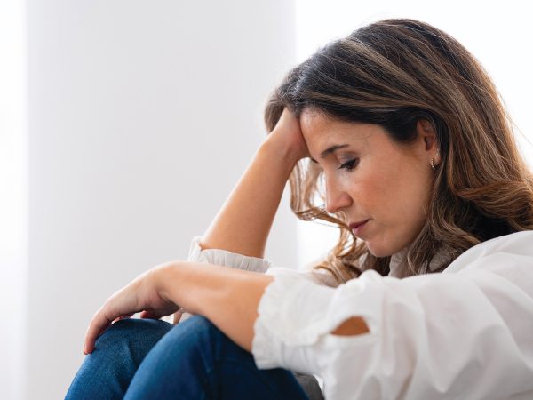 A Woman In A White Blouse Sitting And Resting holding her head