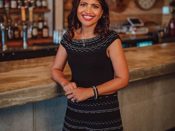 Headshot of a women named Dr. Garima Singh standing in front of a bar