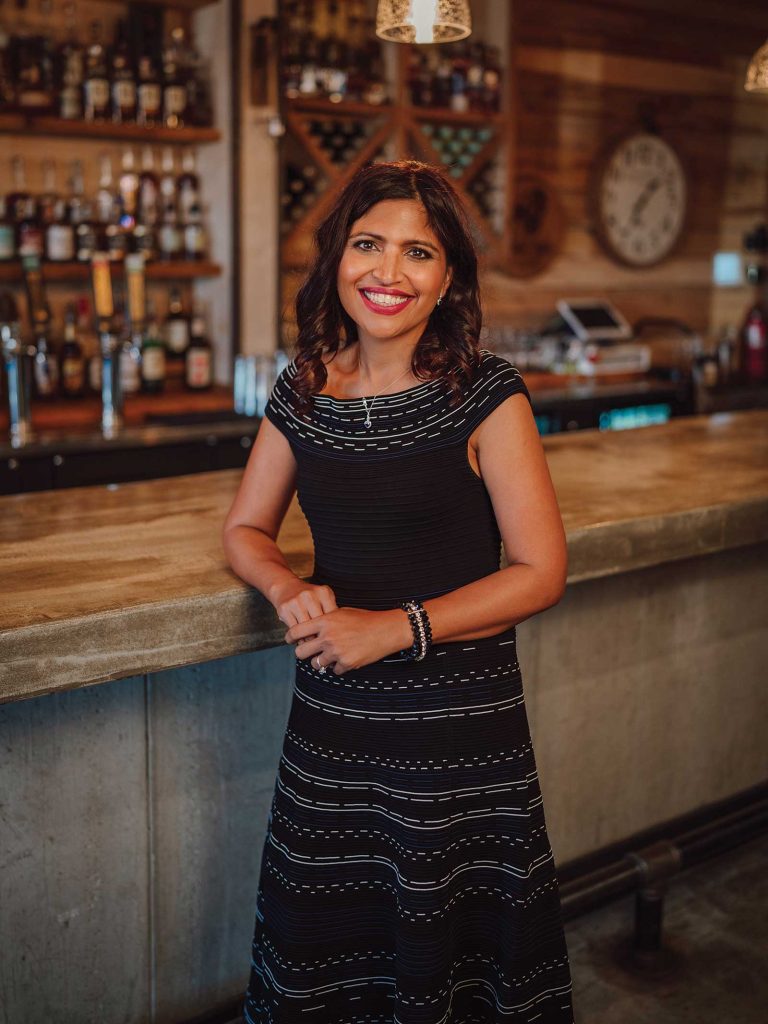 Headshot of a women named Dr. Garima Singh standing in front of a bar