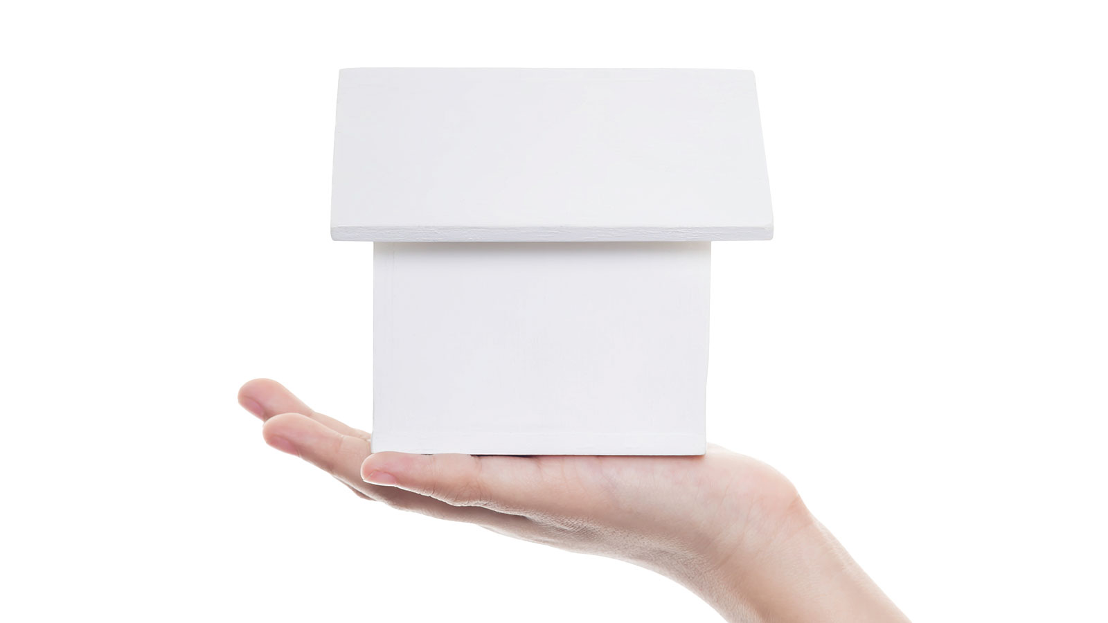 White paper house sitting on an outstretched hand.