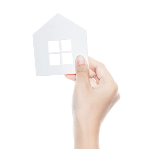 A hand holding up a paper house.