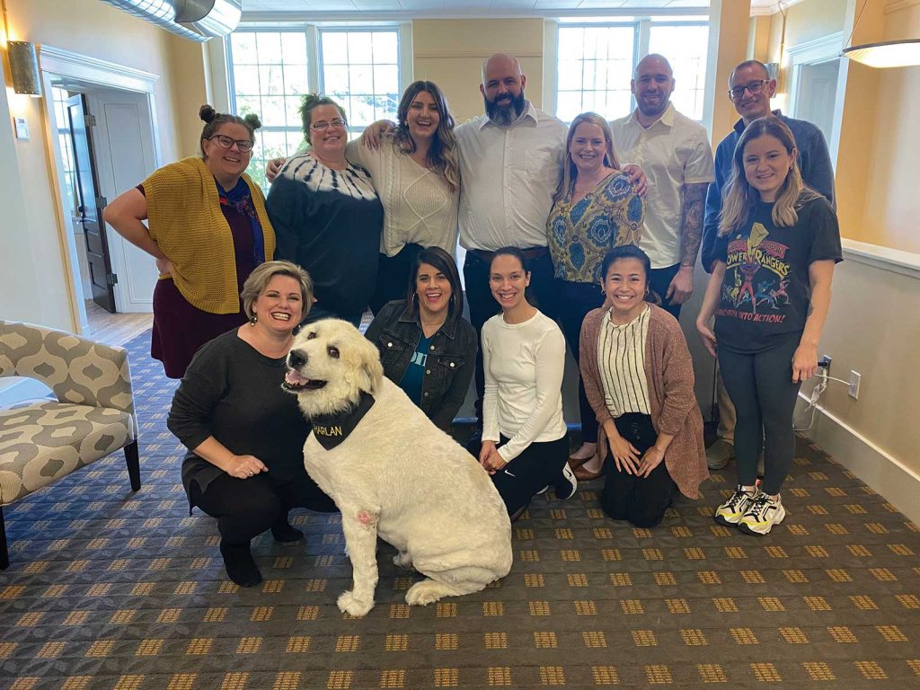 A group of emplyees poses for a image with a large white dog