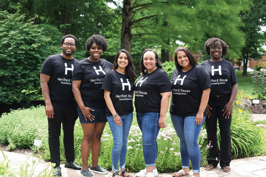 a team of six counselors standing outside by a garden