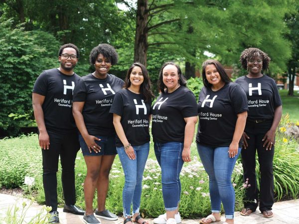 a team of six counselors standing outside by a garden