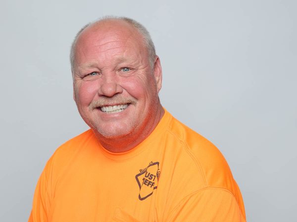 Smiling man in a bright orange shirt with text Just Jeff.