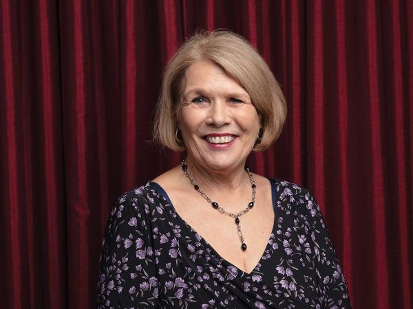 standing in front of a maroon curtain.