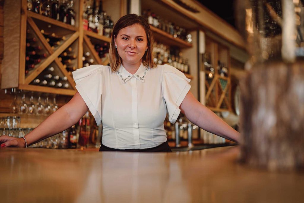 Headshot of a women named Kerri Roberts standing behind the bar counter
