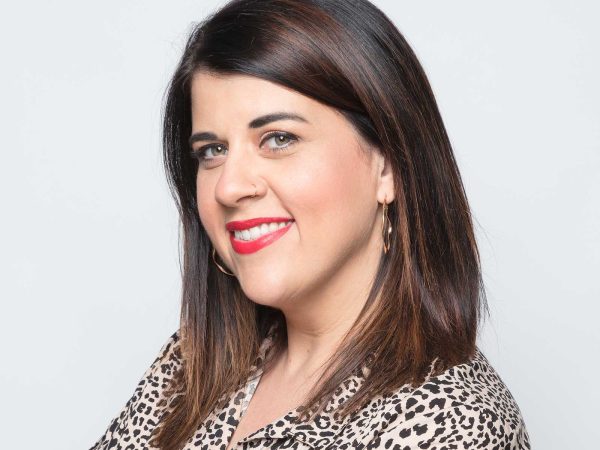 Professional headshot of a women smiling named Kim Ambra against a white background