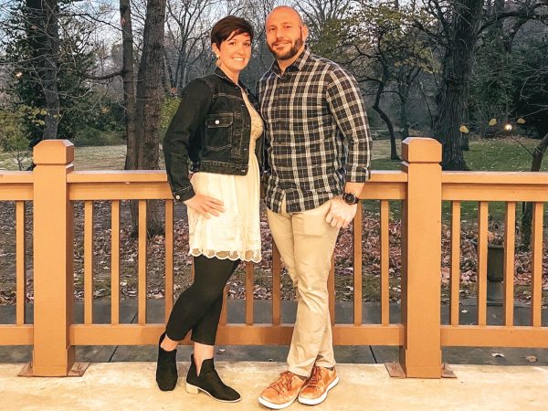 smiling and posing. The woman wears a dress with leggings and a denim jacket