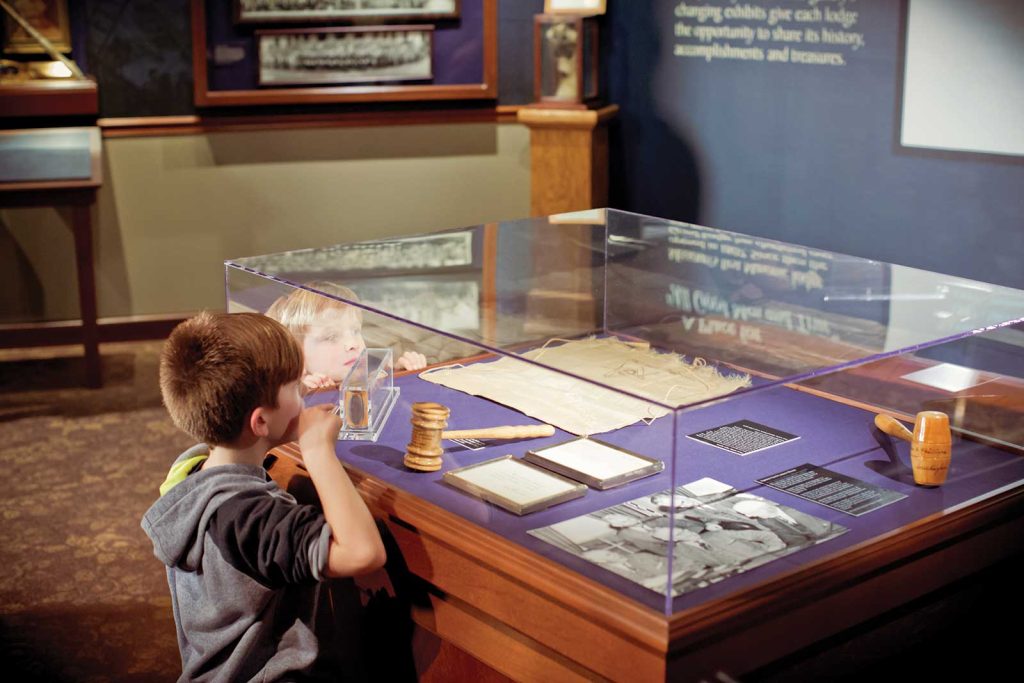 two young boys peer into a display case of items from a masonic museum