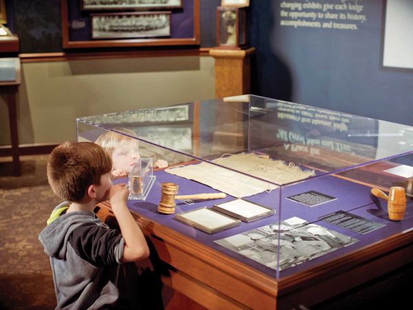 two young boys peer into a display case of items from a masonic museum