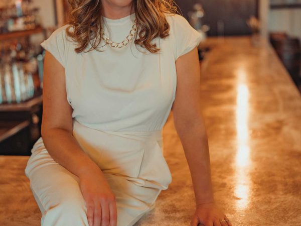 Headshot of a women named Megan Steen sitting on a bar counter top