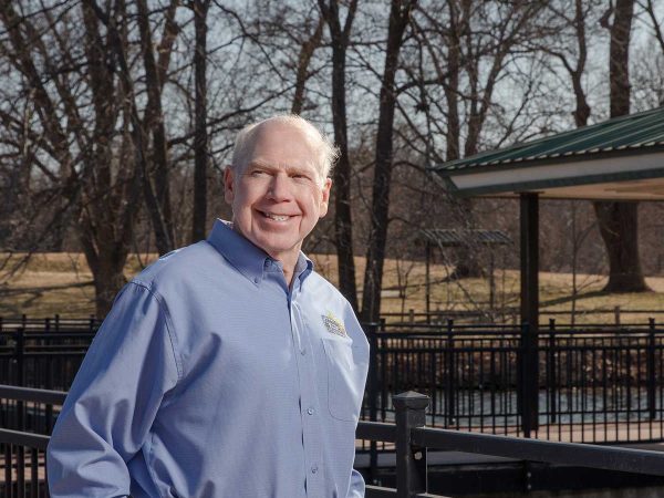 there are bare trees and a pavilion with a green roof. Its a sunny day.