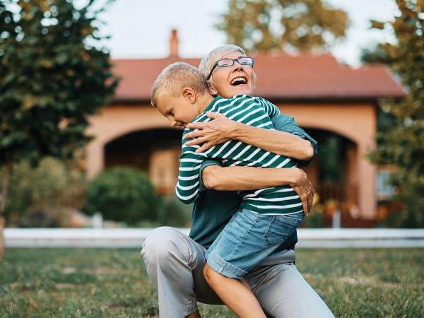 Older woman hugging young child in a yard