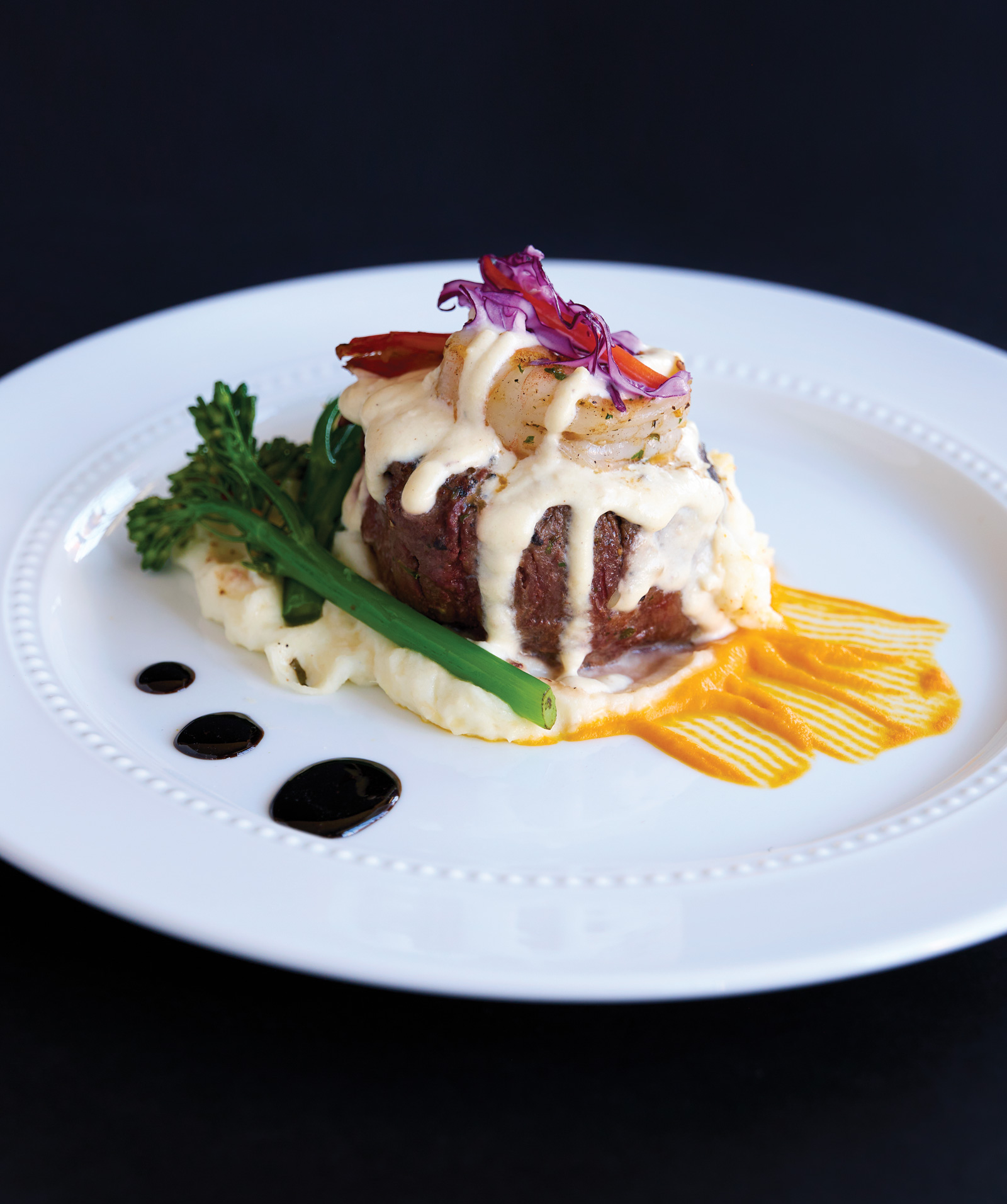 Roasted beef tenderloin over whipped potatoes with broccolini topped with shrimp