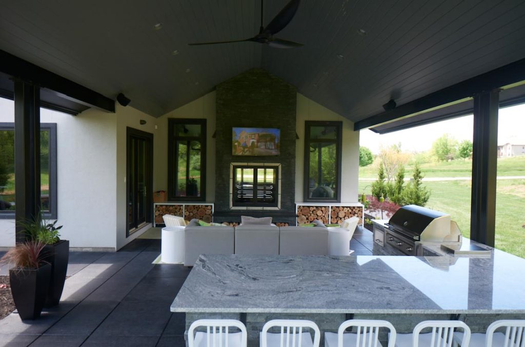 Covered outdoor living space with table chairs couch and TV