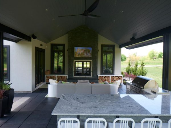 Covered outdoor living space with table chairs couch and TV