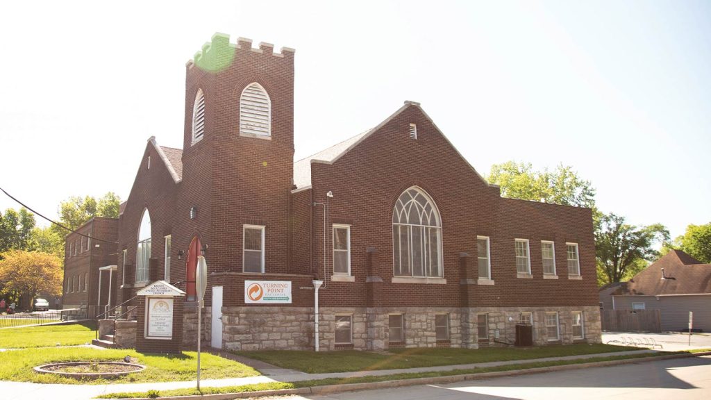 illuminating the building. The church is surrounded by grass and trees