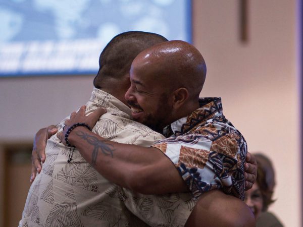 Two men smiling and embracing during worship