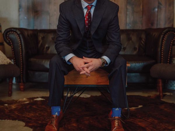 Headshot of a man named Tyson Mutrux sitting on a coffee table with a black couch in the background