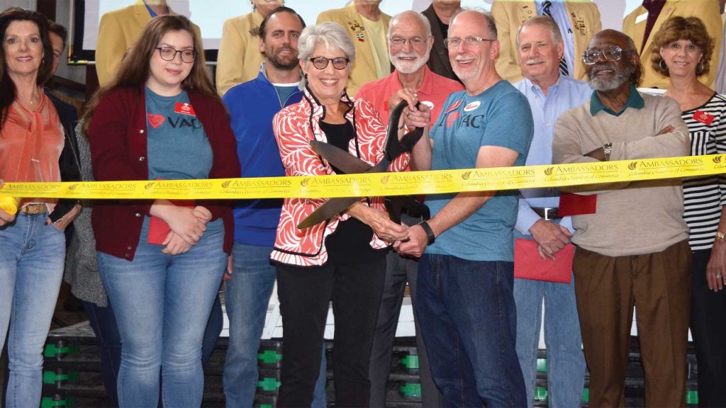 cutting a yellow ribbon. Others stand around them