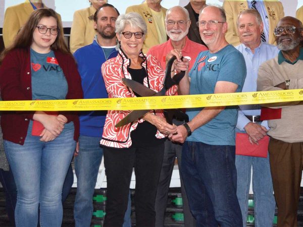 cutting a yellow ribbon. Others stand around them