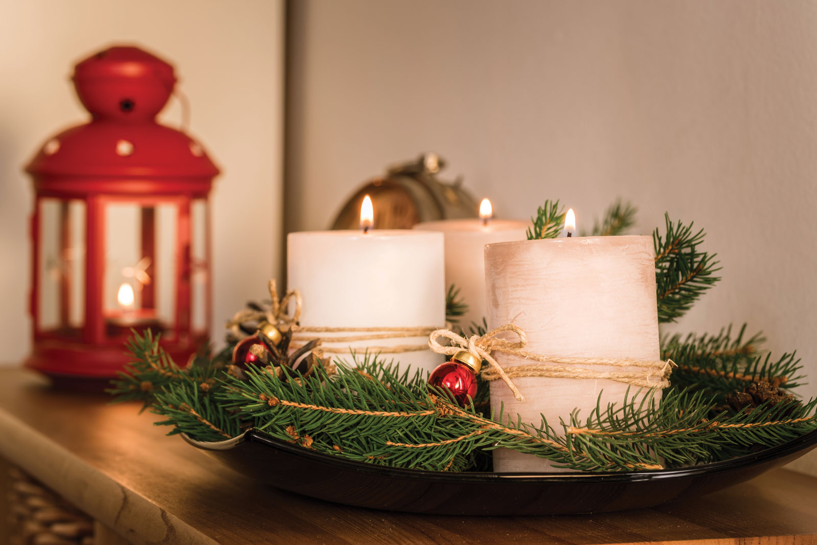 Winter Candles Tied With Greenery In Front Of Red Lantern