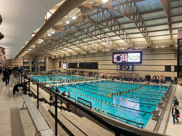 under a high ceiling with skylights. Spectators sit on bleachers