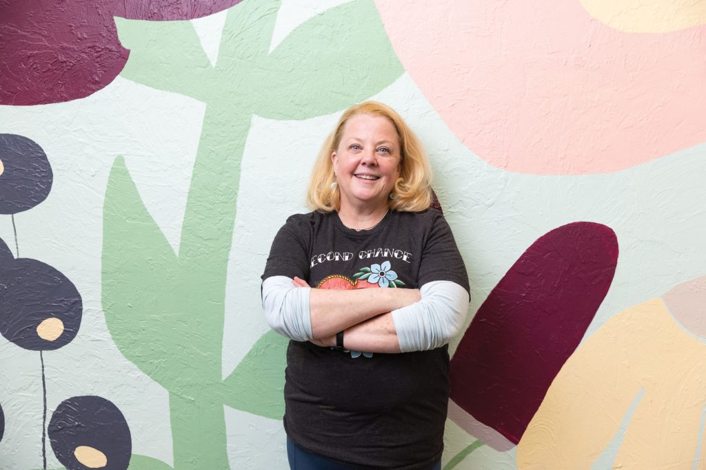 founder and owner of Main Squeeze in Columbia Missouri|Stocked shelves filled with product at Main Squeeze storefront|Leigh Lockhart behind the bakery counter at Main Squeeze|Close up of bakery item and smoothie offered at Main Squeeze|A close up of products in the fridge at Main Squeeze|Interior of Main Squeeze stocked storefront filled with goods|exterior view of Main Squeeze storefront|view of stocked shelves with pantry items at the Main Squeeze|view of decorated shelves with plant propagation jars