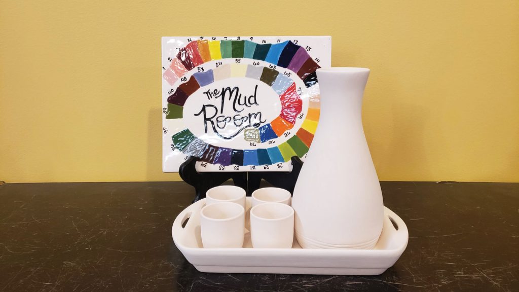 unglazed pottery at a local shop called the Mud Room|Interior room of a local artist shop called the Mud Room with a collection of tables and chairs set against a vibrant red wall|handmade terra cotta bowl resting on a white table at the Mud Room