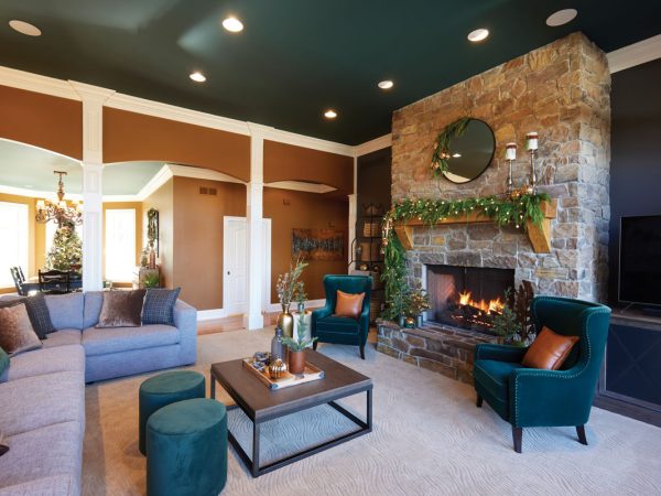 Wide-shot-of-the-living-room-sofa-green-chairs-fireplace-and-adjoining-room-in-the-back