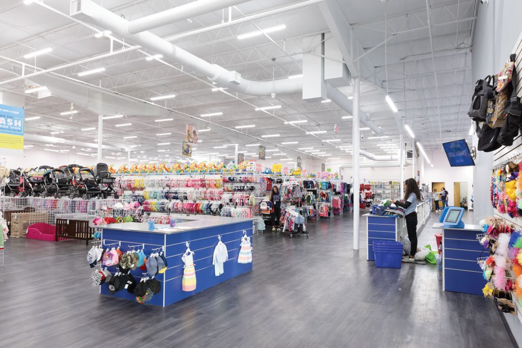 employees sort thorough bins of clothes|Interior of a store with a wall of children's shoes on display|Interior of a children's store with shelves filled with books and toys