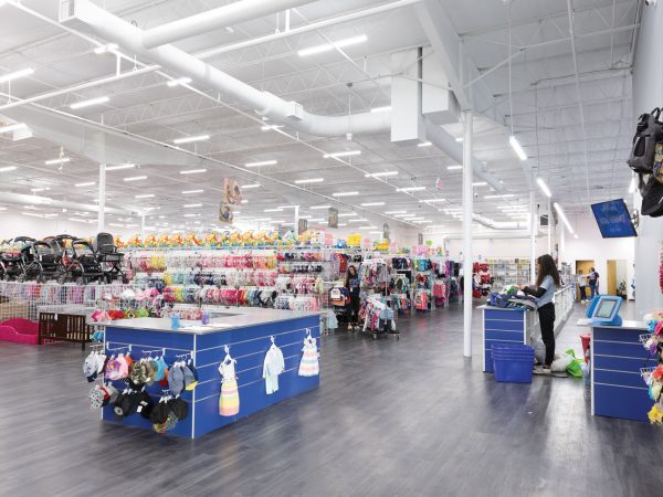 employees sort thorough bins of clothes|Interior of a store with a wall of children's shoes on display|Interior of a children's store with shelves filled with books and toys