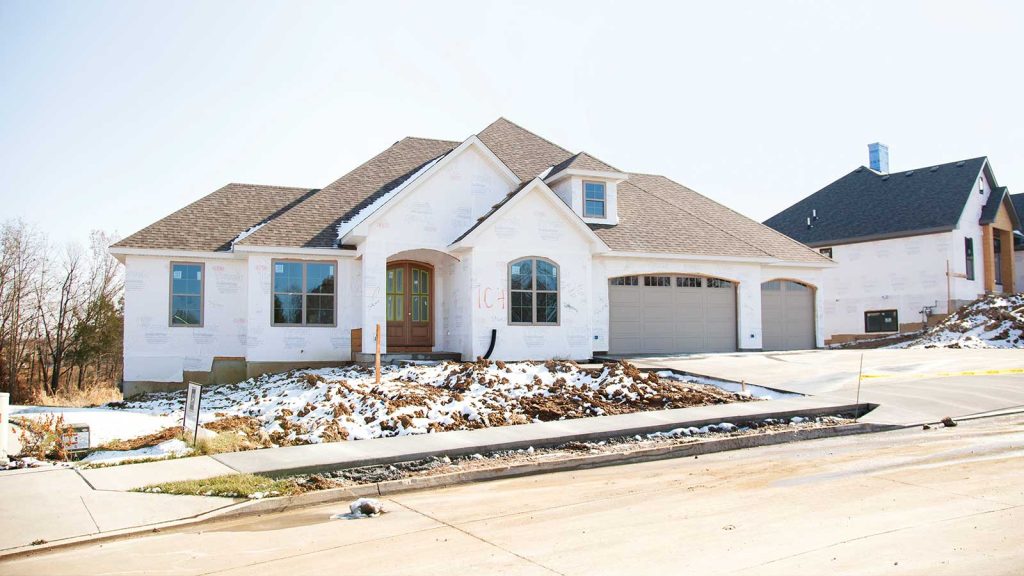 partially surrounded by snow and dirt. The front yard lacks landscaping