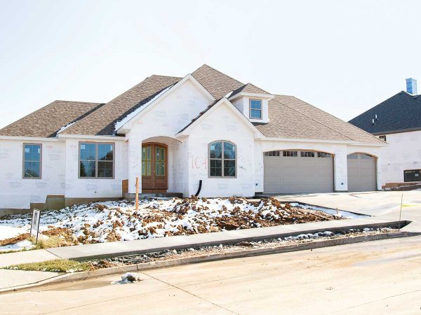 partially surrounded by snow and dirt. The front yard lacks landscaping