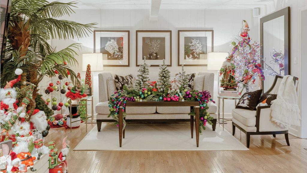with a coffee table in front holding mini Christmas trees and colorful ornaments. Framed art hangs on the wall