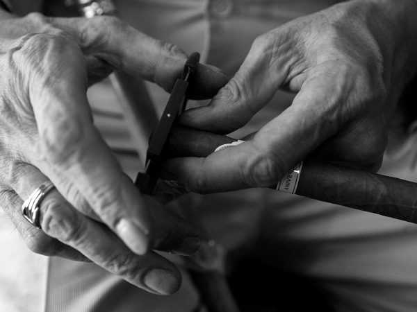 highlighting the texture and details of the skin and objects.|A person holds a lit cigar in one hand