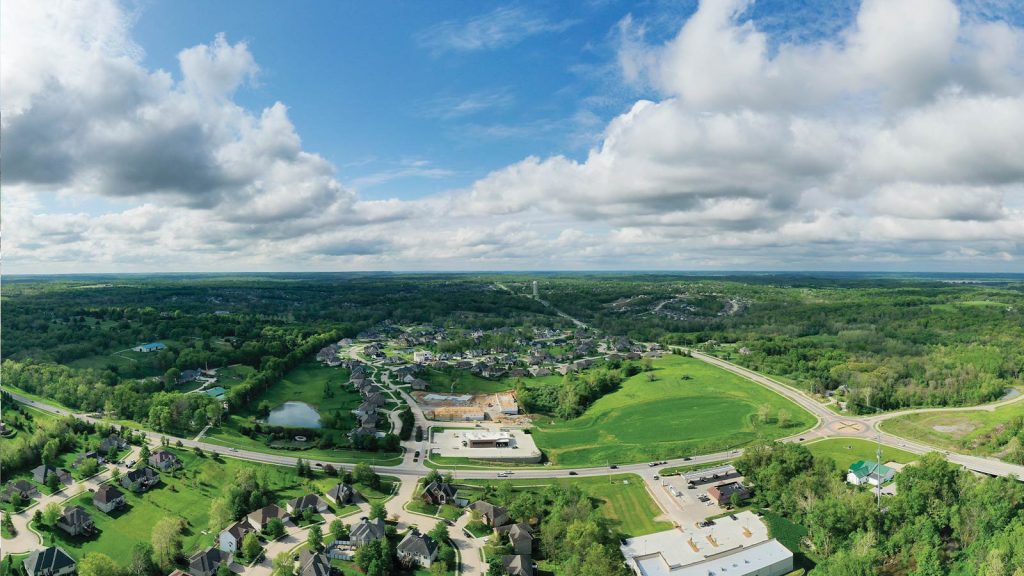 surrounded by trees and fields. The sky is partly cloudy