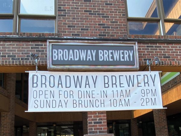 SUNDAY BRUNCH 10AM - 2PM.|A chalkboard with a red frame reads Contactless Pick Up Here in white chalk. A small flower drawing is under the text. The background shows a counter with a red