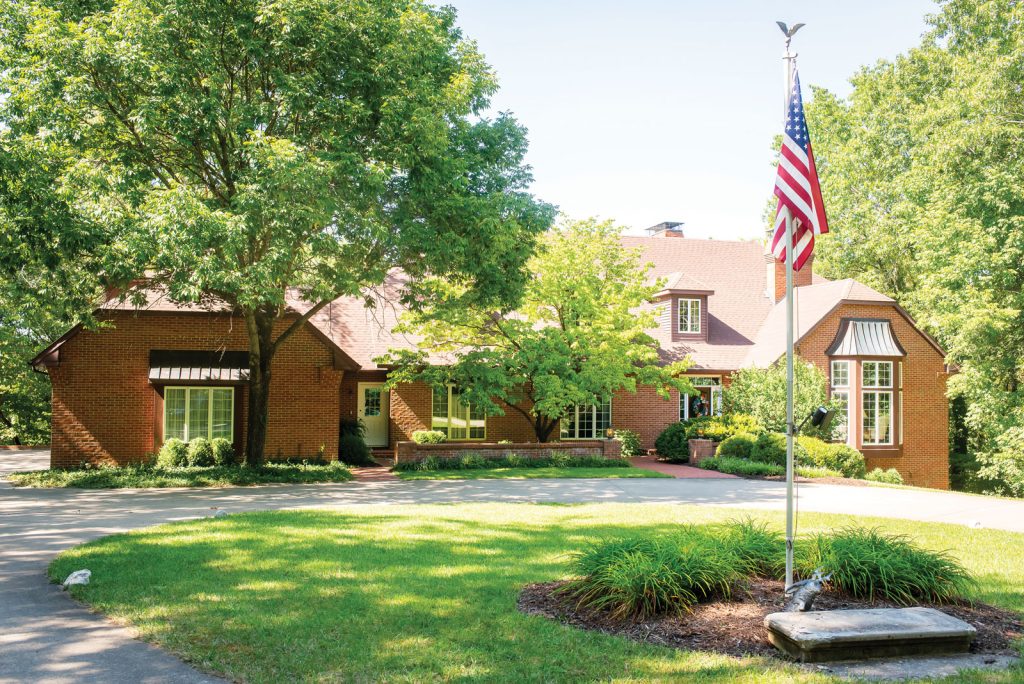 with a circular driveway and well-maintained lawn.|Billiard balls are neatly arranged in a triangle on a pool table in a game room. The background features a table with chairs
