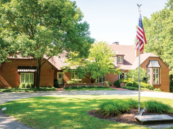 with a circular driveway and well-maintained lawn.|Billiard balls are neatly arranged in a triangle on a pool table in a game room. The background features a table with chairs