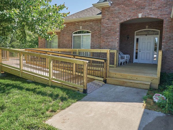 with a white door flanked by two windows. The ramp is lined with safety railings and surrounded by a grassy lawn.|Accessible bathroom with a walk-in shower