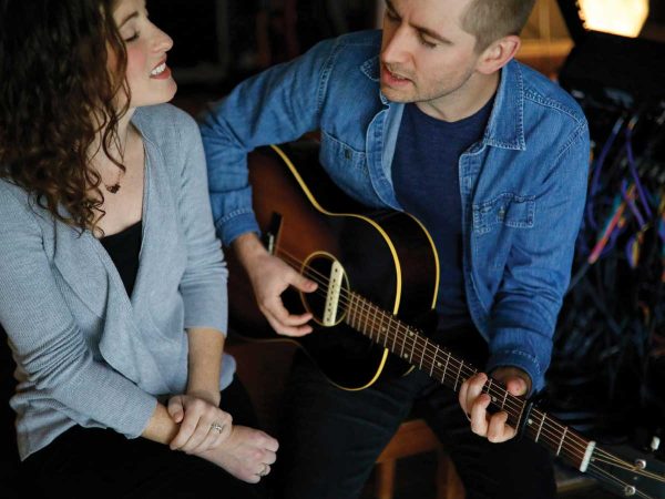 playing an acoustic guitar together. The man