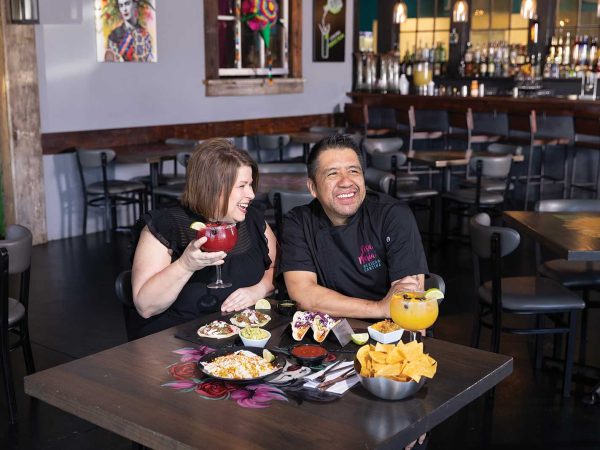 two margaritas served on the table|A couple laughing and sitting at a table in a mexican resturant with two different orders of tacos