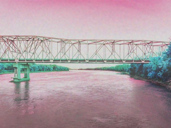 creating a dreamlike atmosphere.|A metal truss bridge spans a wide river with dense foliage on both banks. The image has a pinkish hue