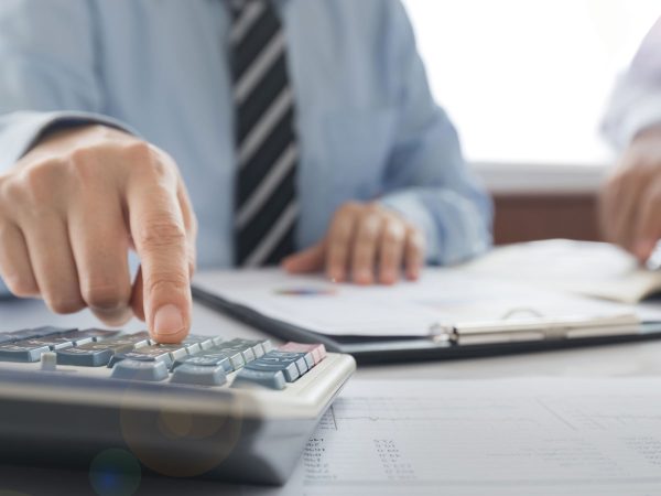 man-in-tie-working-with-a-calculator-and-financial-documents