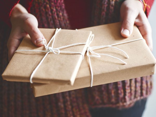 person-holding-books-wrapped-in-brown-paper-tied-with-string