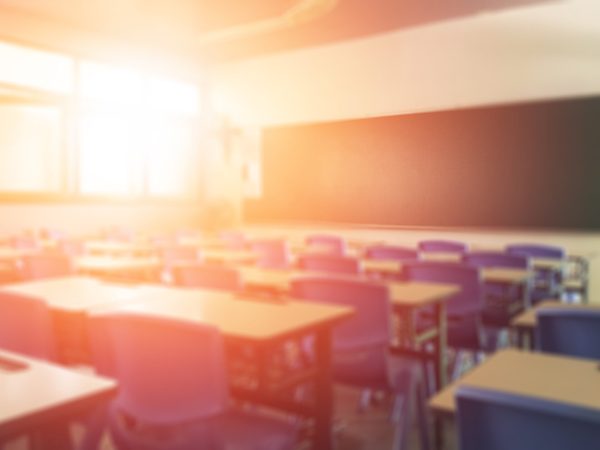 School classroom in blur background without young student; Blurry view of elementary class room no kid or teacher with chairs and tables in campus.